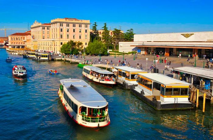 Canal boats depart from a stop just outside a train station in Venice.