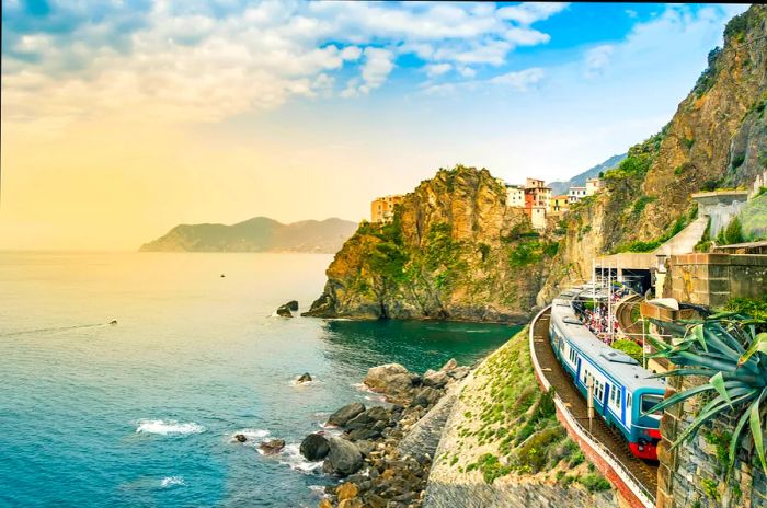 A train approaches a tunnel at a coastal station.