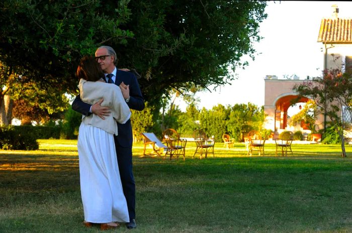 A couple twirls on a lush green lawn.