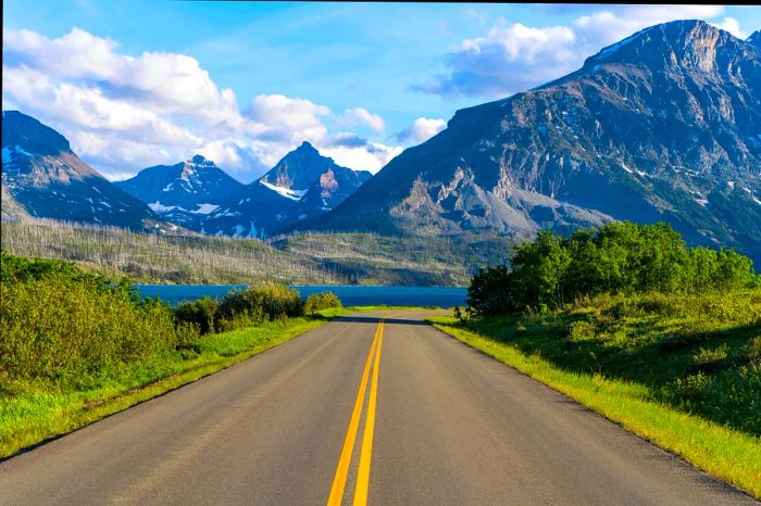 A scenic road winds down towards a lake in the mountains