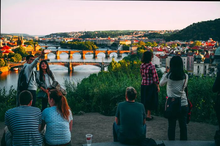 A group of people enjoying a sunset view over a city with a river flowing through it