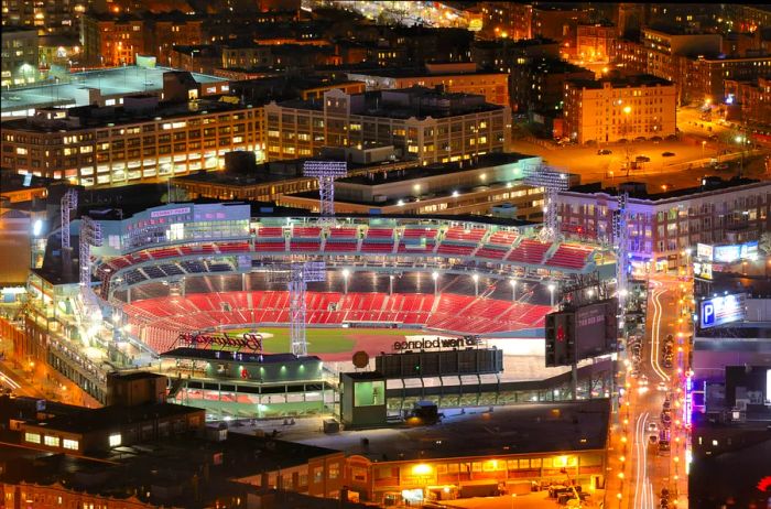 An aerial view of a brightly illuminated sports stadium in an urban setting