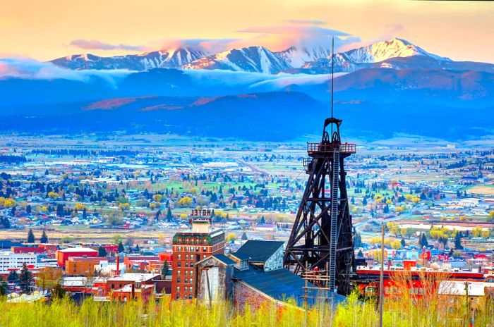 A mining shaft located at the edge of a town, framed by a mountain range.