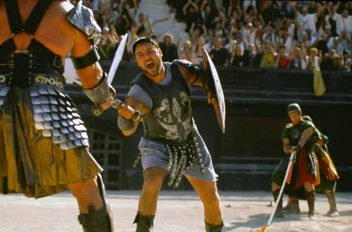 A man clad as a Roman gladiator battles another man in a vast arena