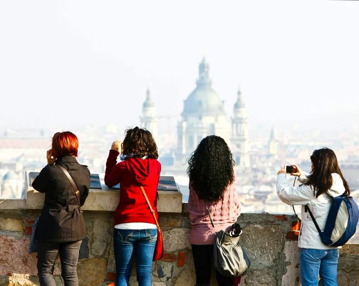 Four female tourists capturing photos of Budapest with the basilica visible in the background