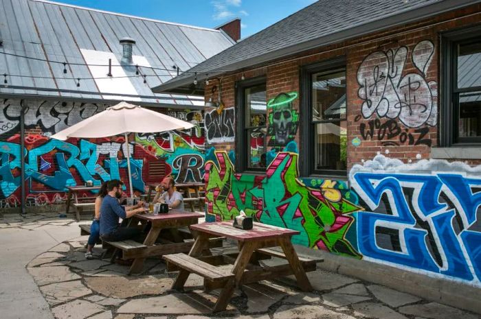 Colorful graffiti adorns the walls of a popular barbecue joint, complete with outdoor picnic tables