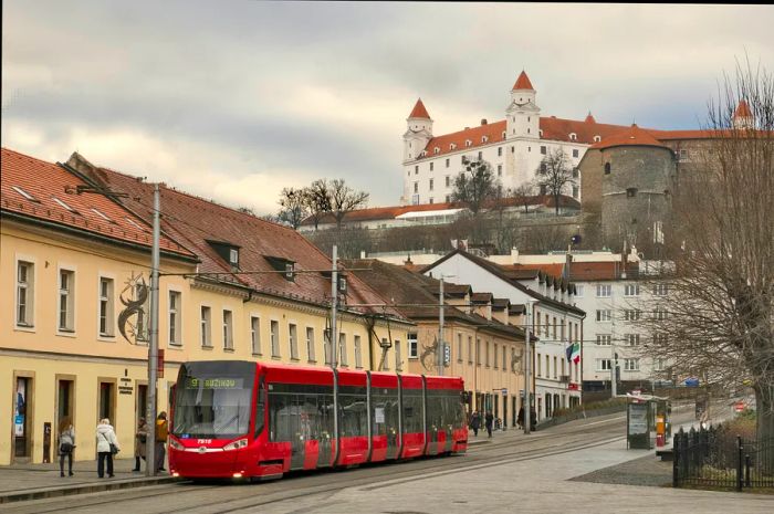 A tram glides through the Old Town, with Bratislava Castle visible in the distance, Bratislava, Slovakia