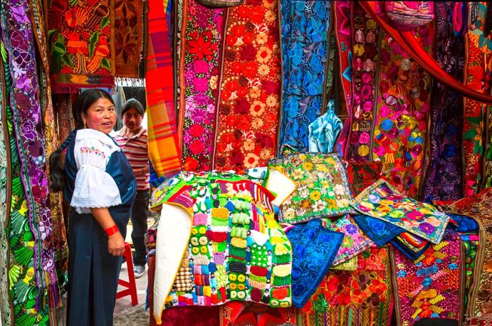 A vendor showcases colorful handicrafts in the market of Otavalo, Ecuador.