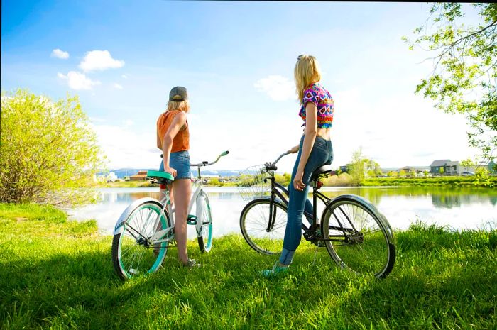 Two female cyclists pause by a lake near Bozeman