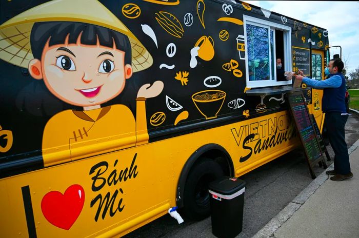 Phan serves customers at the Vy Banh Mi food truck in Portland, Maine, USA