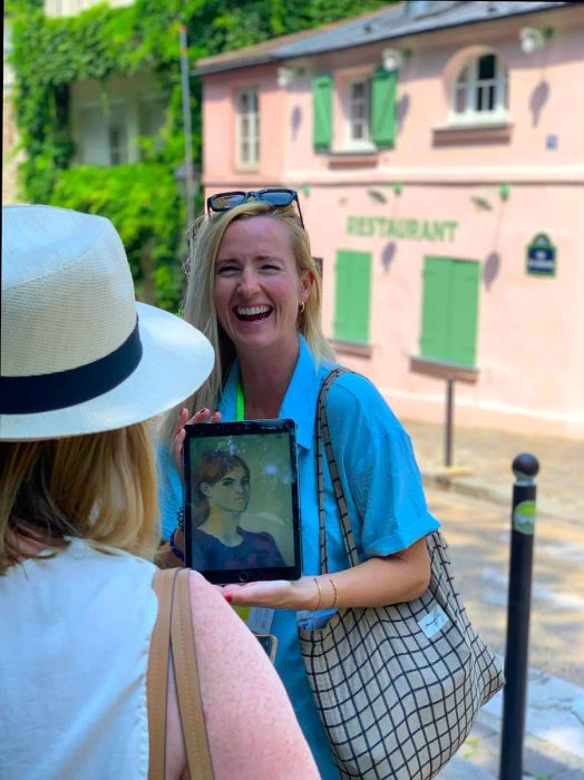 A tour guide beams while sharing a story about the woman in the photo she holds