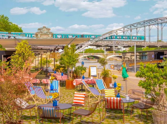 A riverside terrace bar adorned with numerous striped deckchairs