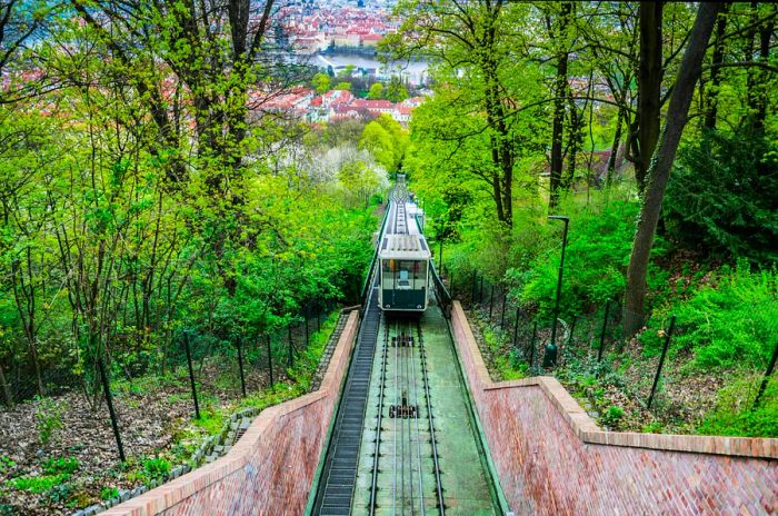 A view down a funicular track towards a green train carriage