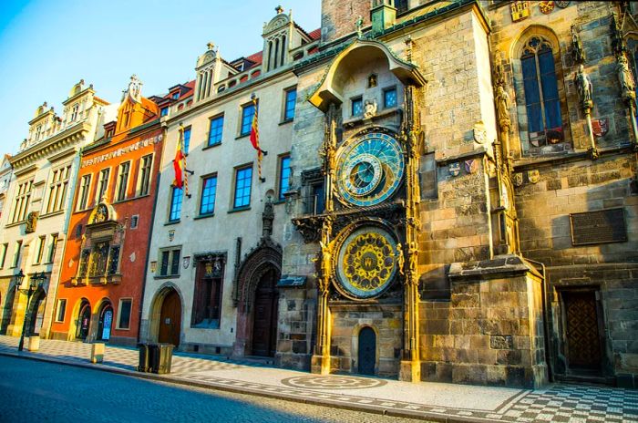 A grand astronomical clock with multiple faces adorns the side of a three-story building.