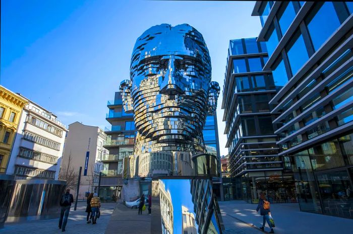 A massive metallic sculpture of the writer Franz Kafka is located in the middle of a street in Prague.