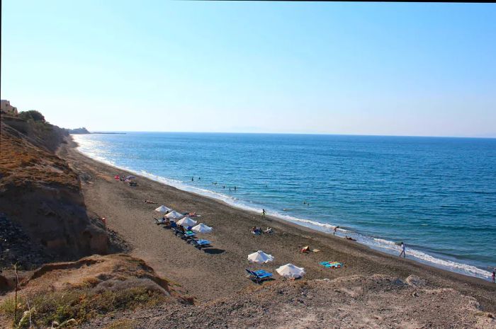 Baxedes Beach, adorned with a few sun loungers under the sun on a clear day.