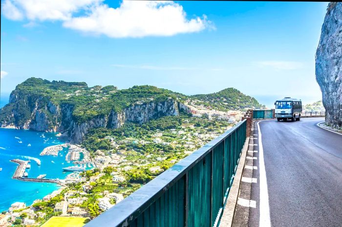 A bus navigates a winding road along a rocky cliff in the Amalfi Coast, Catania, Italy