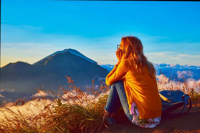 A woman enjoys the sunrise atop Mt Batur, Bali, Indonesia