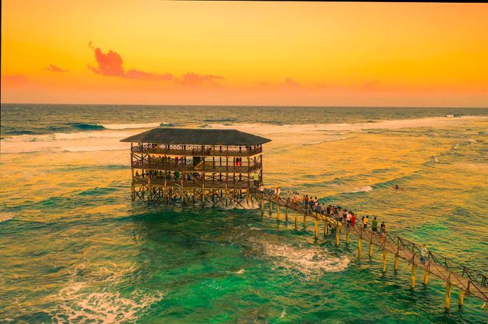 An expansive, multi-level wooden structure extending into the sea near a popular surf location.