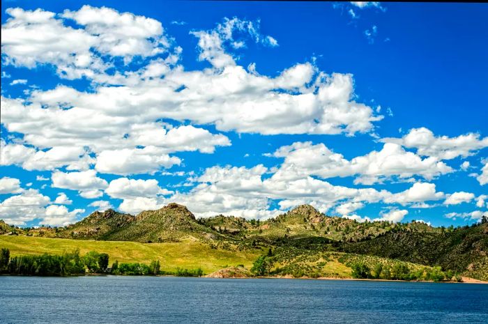 Crystal Lake sparkles in the sunlight, nestled among grassy hills at Curt Gowdy Park, Wyoming.