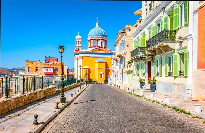 Vibrant scene featuring a cobblestone street with colorful buildings and lanterns in the heart of Ermoupoli, Syros, Greek Islands.