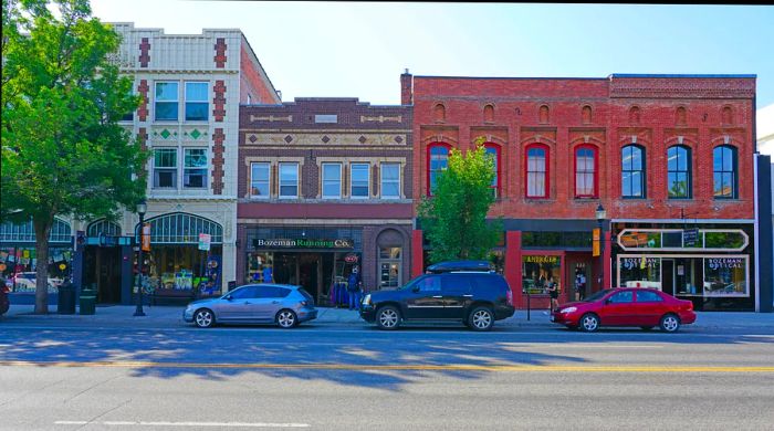 A sunny day showcases a row of shopfronts in a charming town.