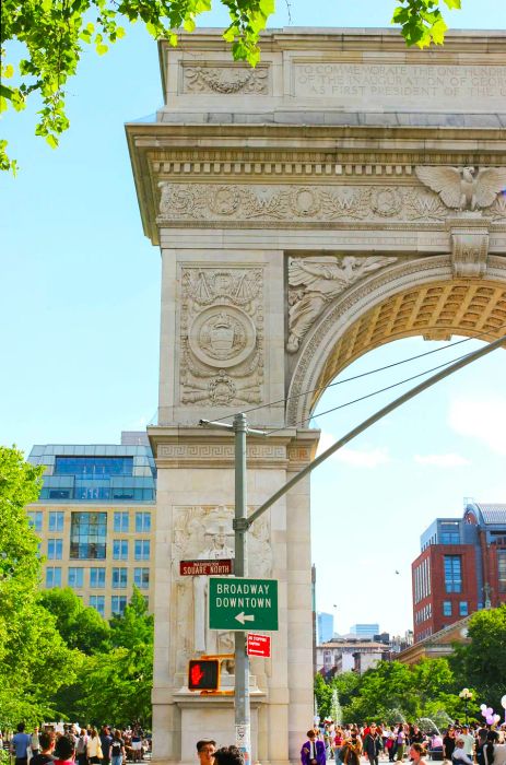 A grand white stone archway with a street sign reading Washington Square North