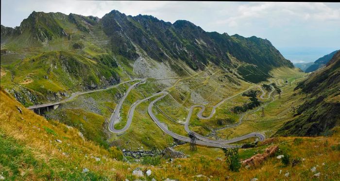 A winding mountain road weaves through lush green hills.