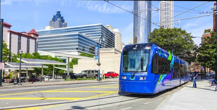 The Atlanta Streetcar located at Olympic Park Station with the city skyline behind it