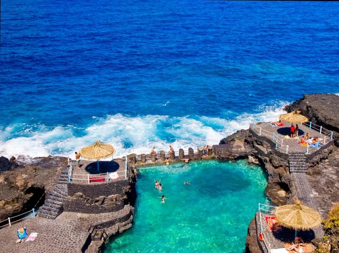 Visitors swim in a natural pool on the dark volcanic beaches of La Palma.