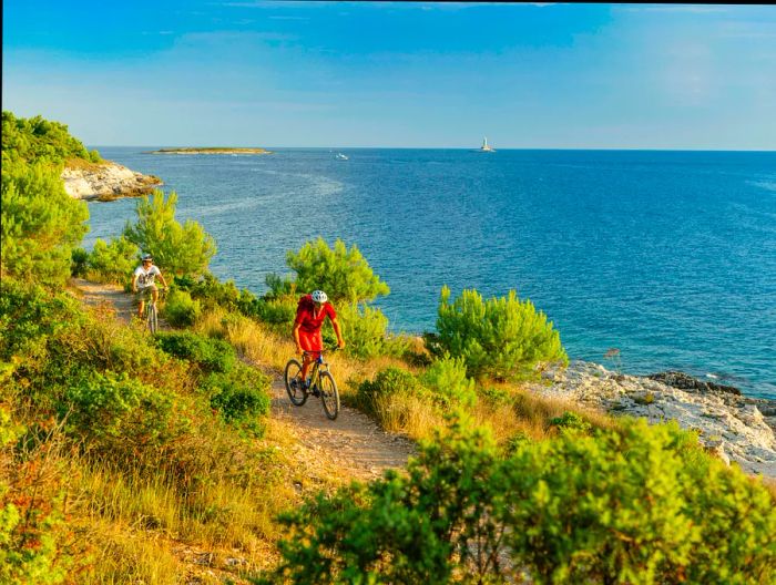 Cyclists navigating the paths at Cape Kamenjak, tracing the rugged coastline.