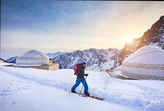 A skier with a backpack glides past yurts at Shymbulak near Almaty, Kazakhstan