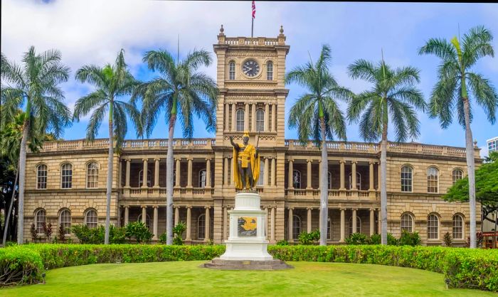 The facade of a grand palace surrounded by a garden lined with palm trees