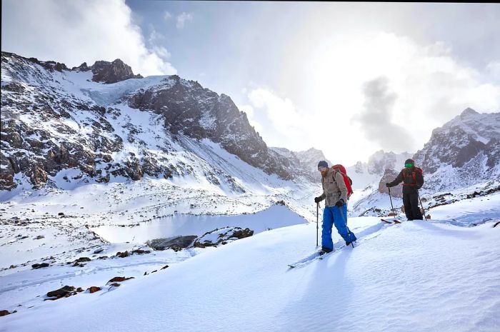 Two individuals ski touring amidst Kazakhstan's snowy mountains