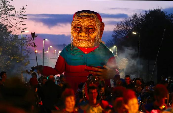 A large, eerie float depicting a spooky figure hovers over Galway during a Halloween parade.