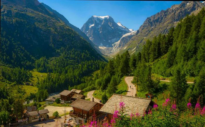 A trekker strolls along a road lined with wooden chalets that leads into the mountains