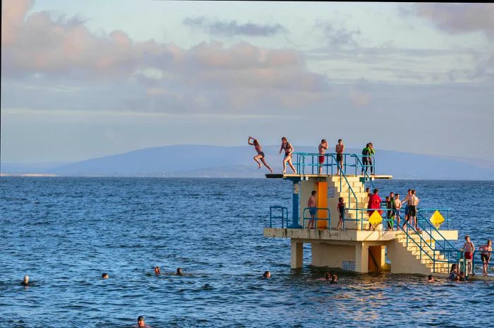 People leap from the Blackrock Diving Tower in Galway at high tide.