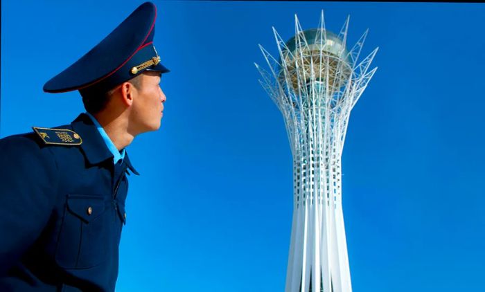 A military cadet gazes up at Baiterek Tower in Astana, Kazakhstan