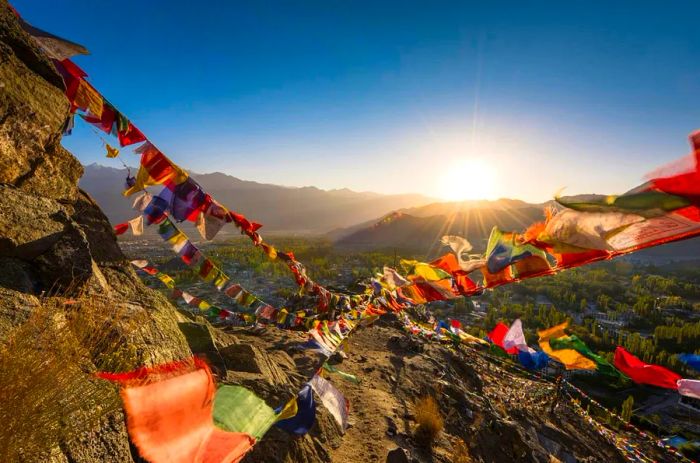 Vibrant Buddhist prayer flags dance in the wind as the sun rises over majestic mountains