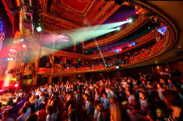 Students leap from their seats to dance during the finale of a traditional pantomime performance.