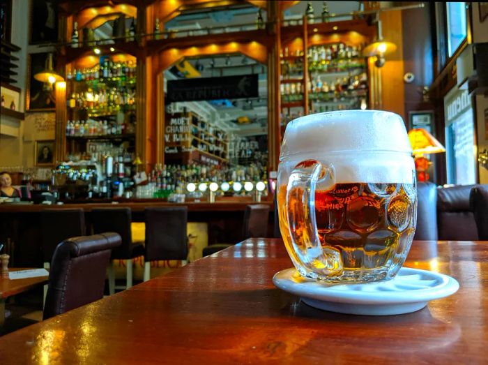 A large jug of beer with a frothy head on a table in a pub