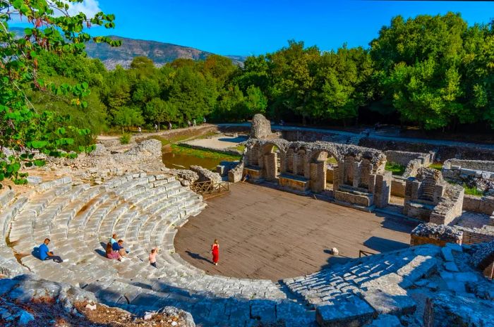 A Roman amphitheater featuring a few tourists admiring its architecture.