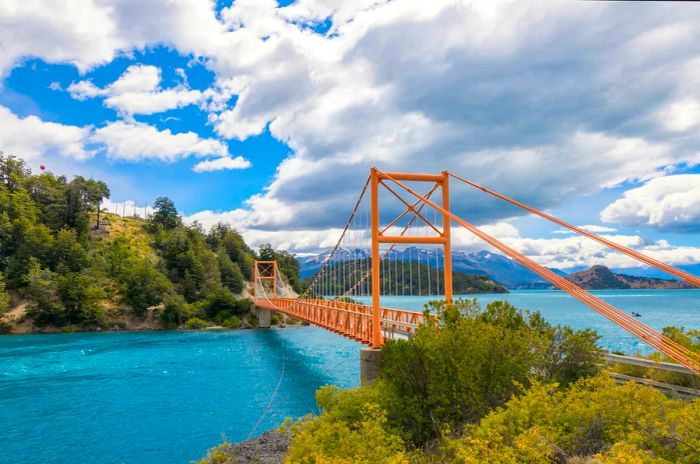 A striking red road bridge spans over turquoise glacial lakes.