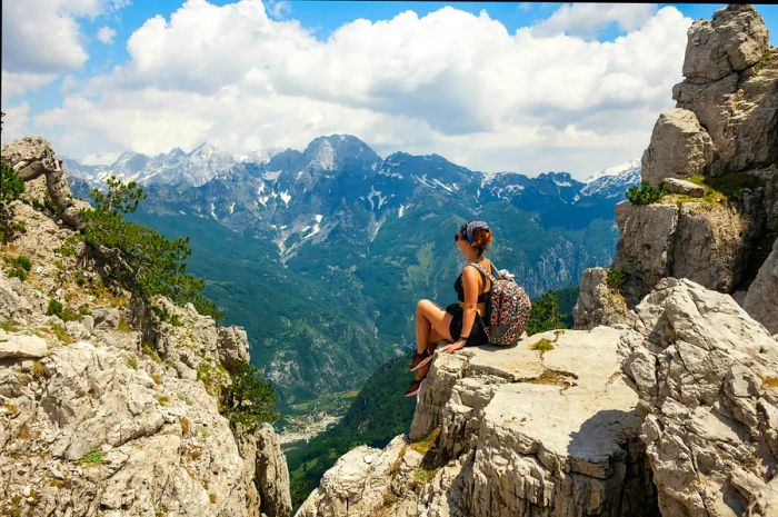 A woman relaxes at the edge of a hiking trail in the Albanian mountains.