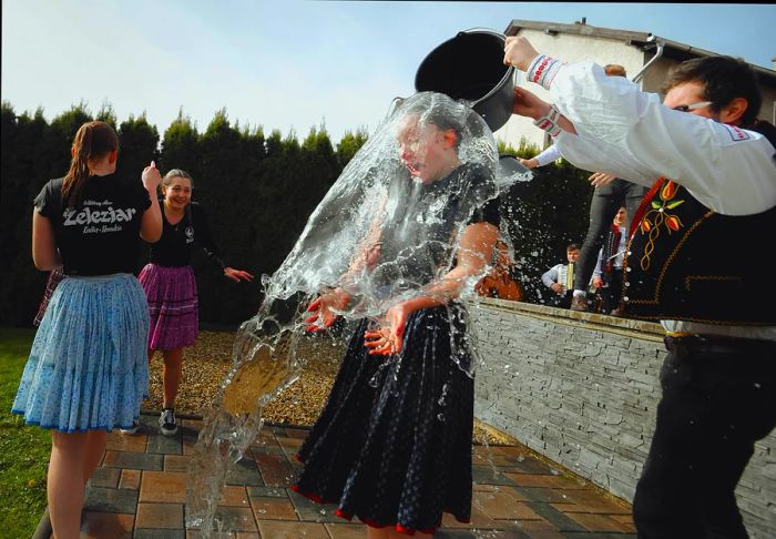 During Easter in Bociar, Slovakia, male members of the Zeleziar folk dance group playfully whip and splash water on local girls dressed in traditional attire.