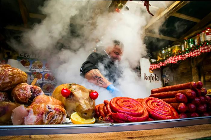 A man grills various meats at a food stall during the Christmas market at Hviezdoslavovo námestie in Bratislava's Old Town.