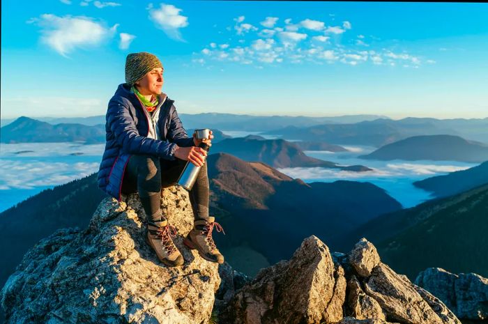 A young hiker stands atop a mountain peak, gazing over a sea of clouds in Slovakia.