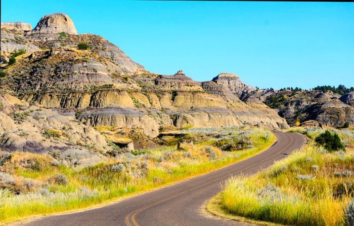 A winding road cuts through colorful sedimentary rocks in Montana.