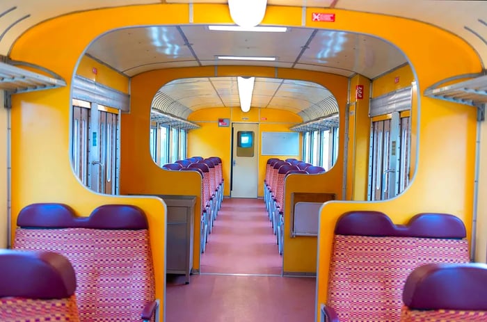 The nostalgic interior of a vacant train carriage, featuring symmetrical seating and decor