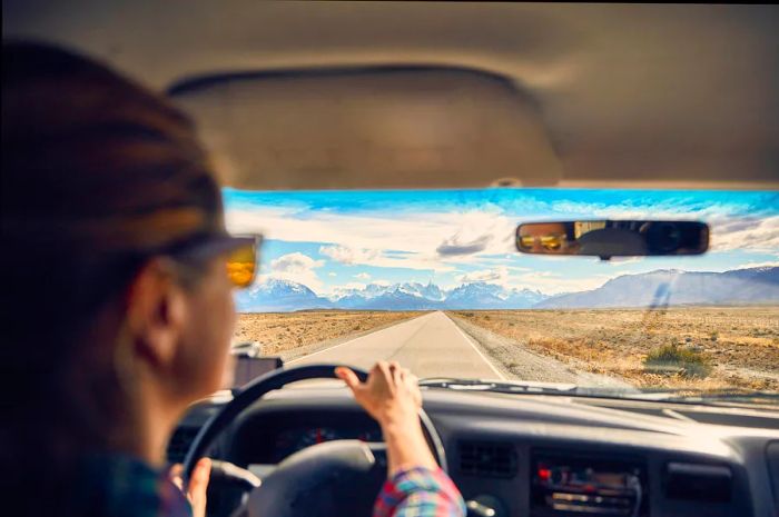 A driver's perspective through the windshield, looking down a road towards a mountain